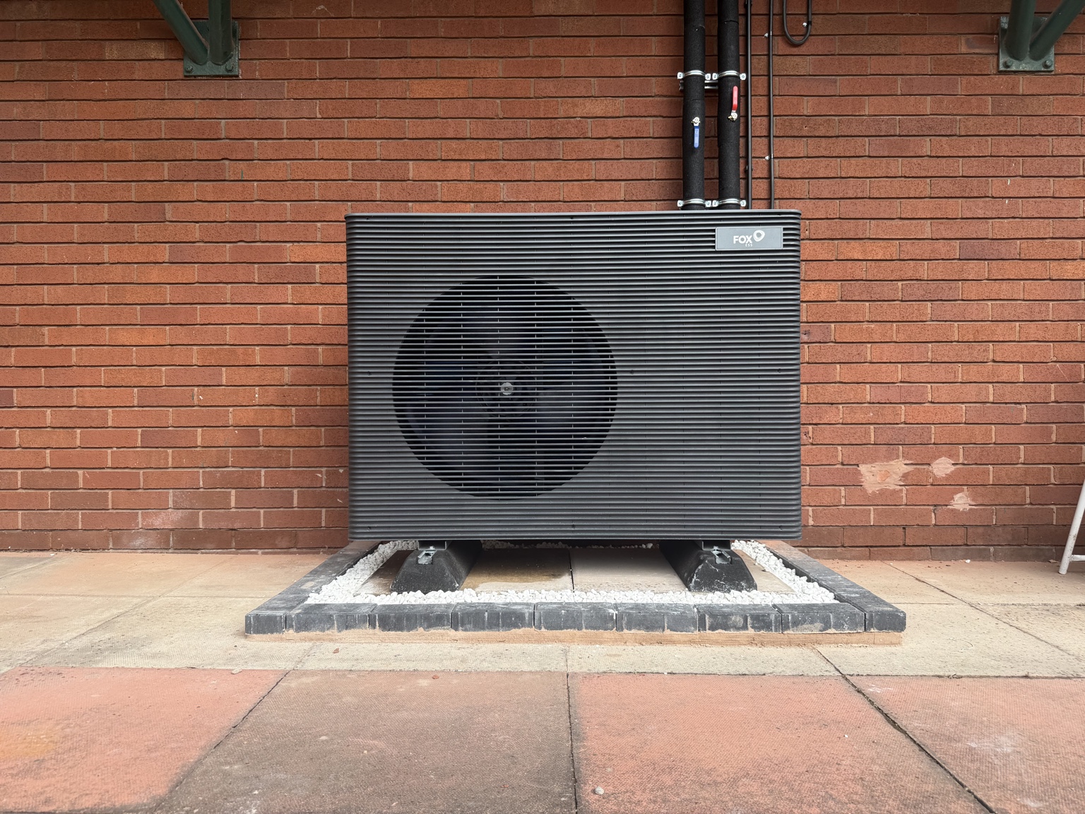 Completed outdoor heat pump installation with a neat gravel base